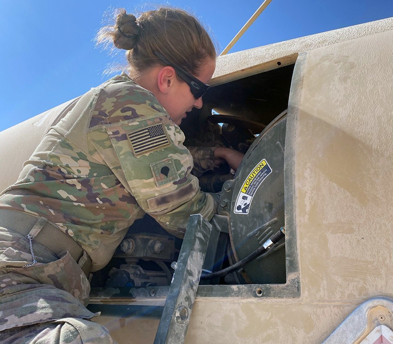 An Army Soldier on a ladder inspects inside a compartment on an aircraft.